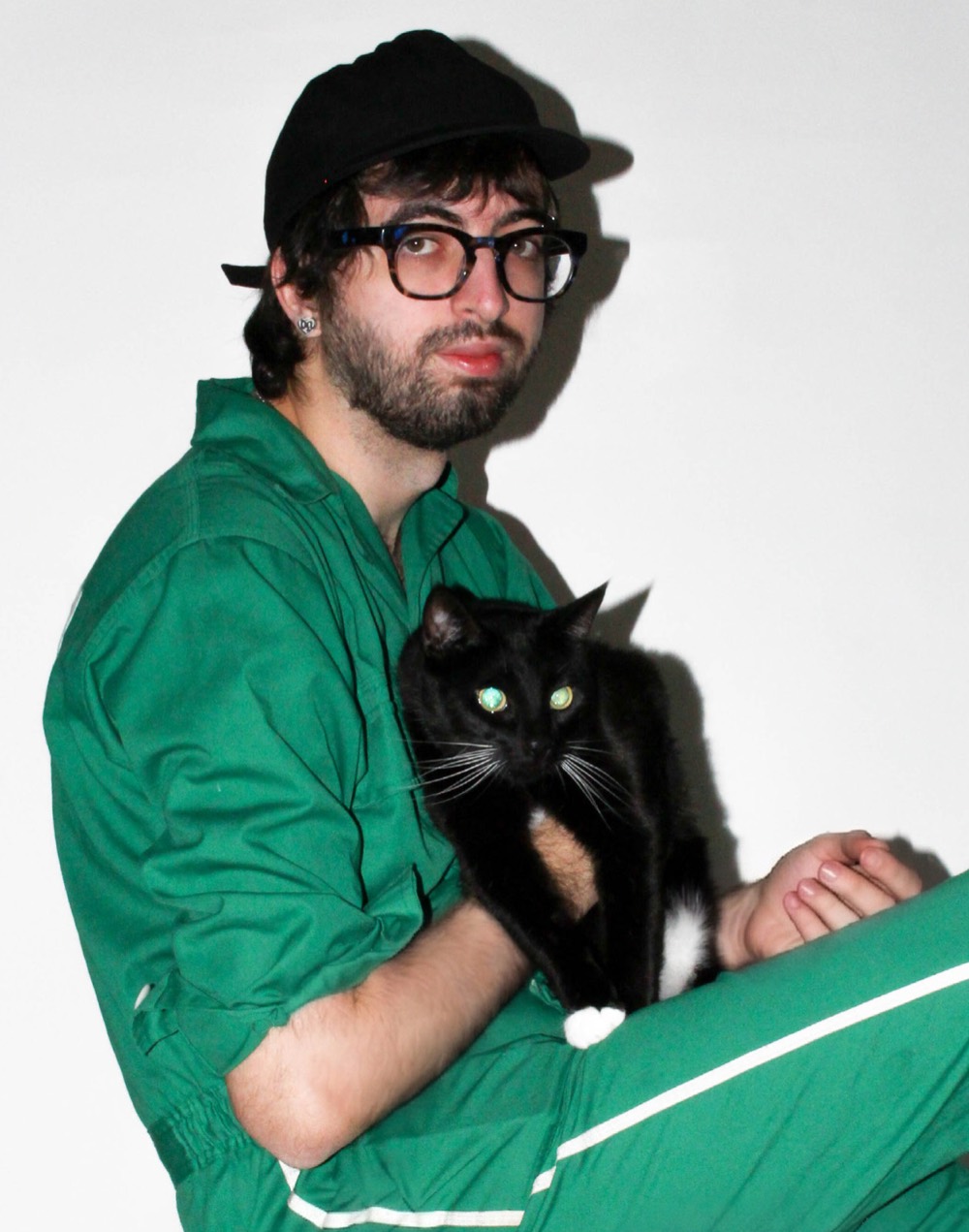 Cameron Nayeri in a green tracksuit, holding his black cat